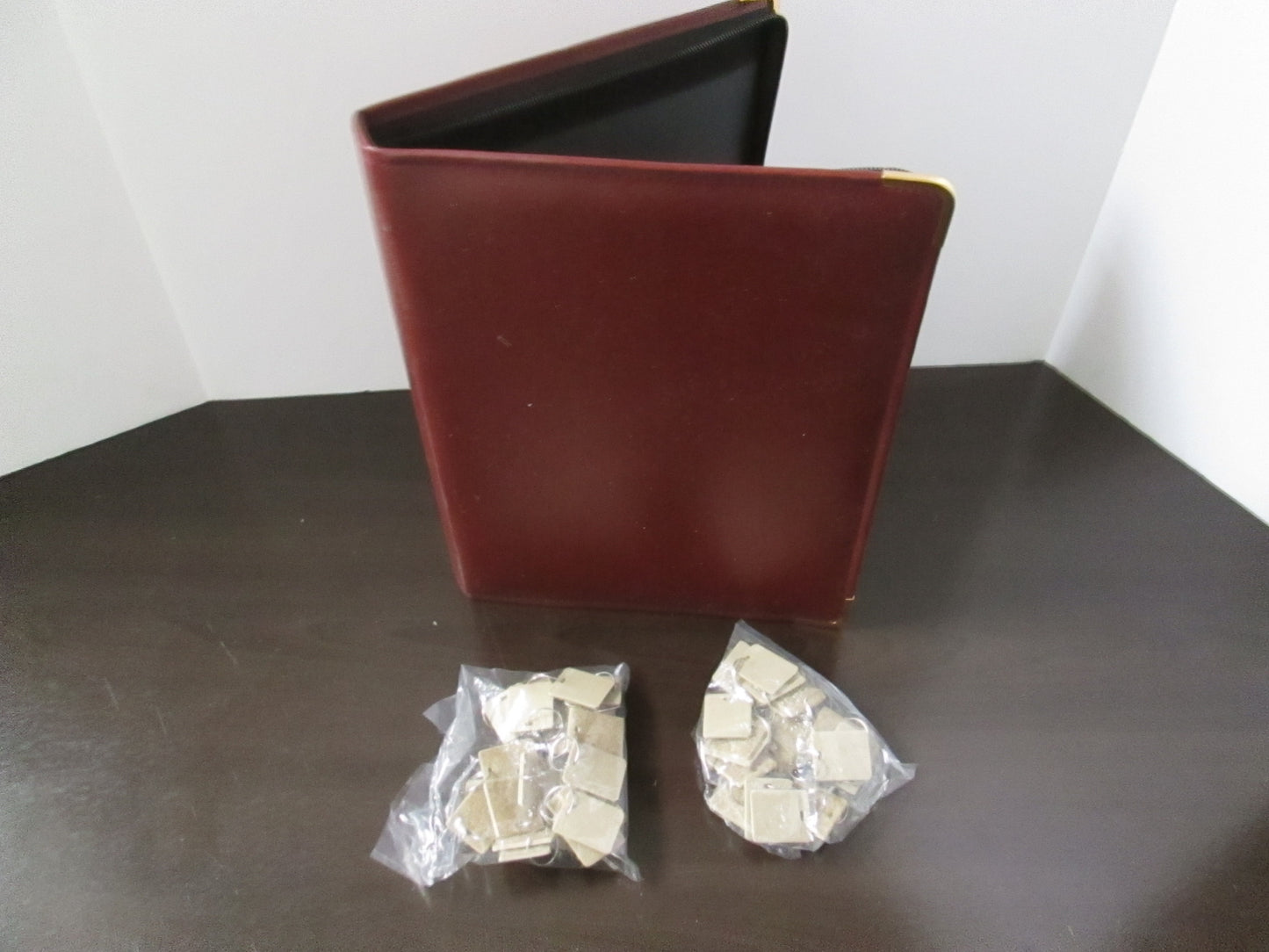 A burgundy vinyl key case with a heavy duty zipper, designed to hold 48 key tags, displayed with the key tags visible in an open condition.