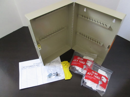 A door-mounted key cabinet with a combination lock, shown open with numbered key tags and a few spare keys, mounted on a sheet of paper for scale.