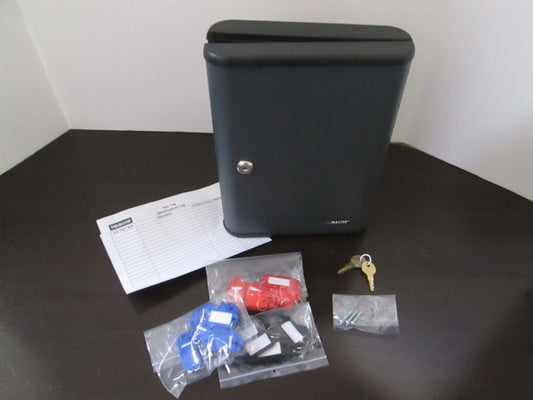 A gray metal key storage cabinet with hook-style key hangers, a cam lock on the door, and two keys. The cabinet is on a table with a paper with '30' on it, indicating its capacity to store 30 keys.
